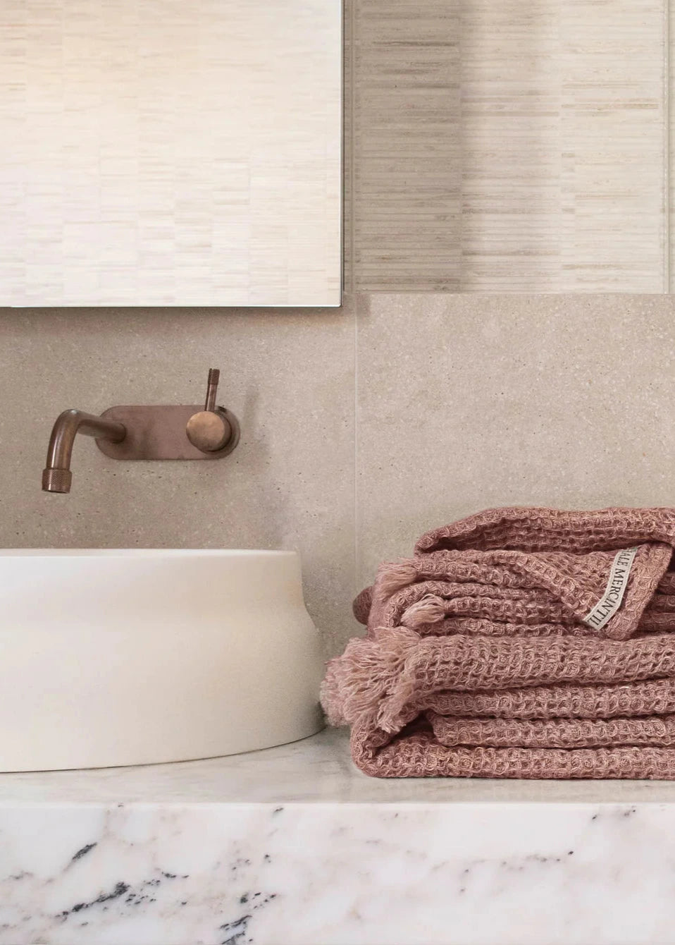 Folded pink towel on a marble countertop with a neutral bathroom background