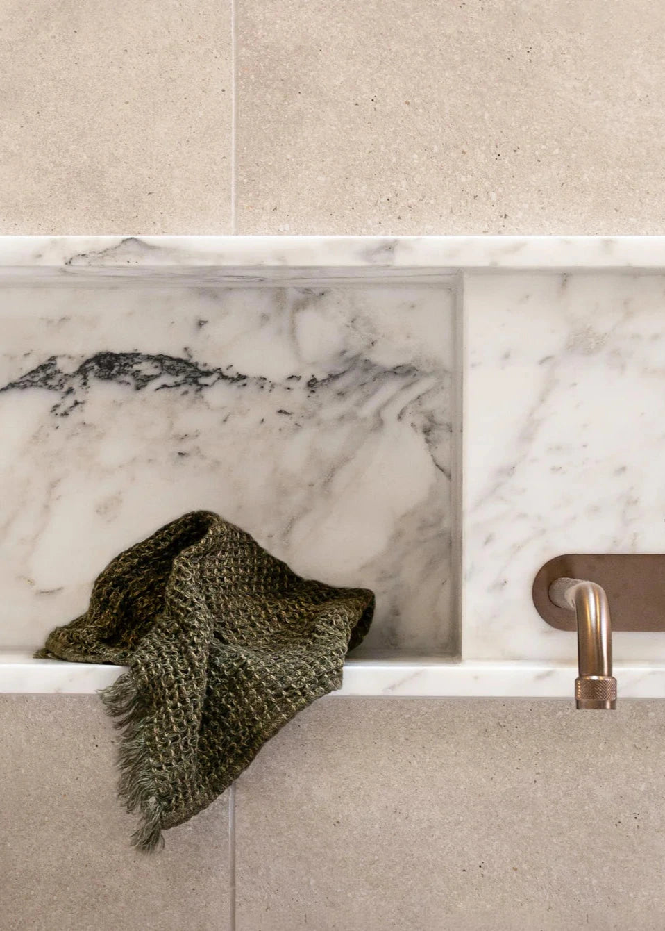 Marble-framed sink with a towel and faucet in a bathroom setting